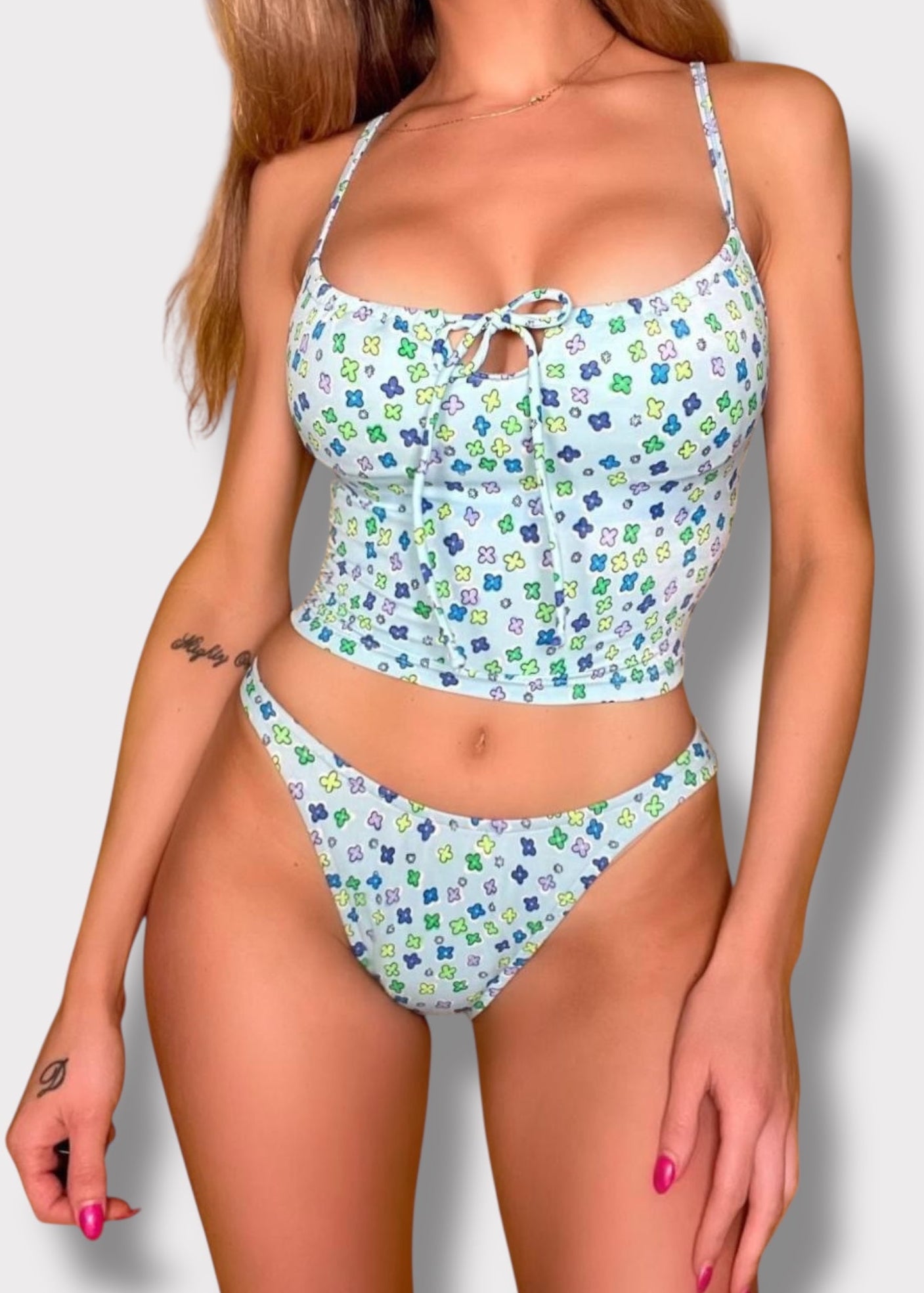 Woman wearing a floral two-piece swimsuit on a plain background