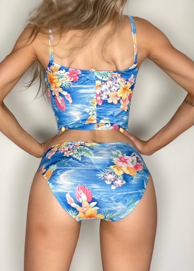 Woman wearing a colorful floral two-piece swimsuit against a plain background