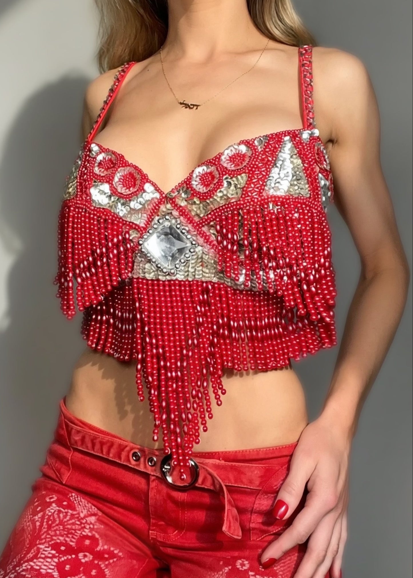 Person wearing a red beaded top and matching pants against a neutral background