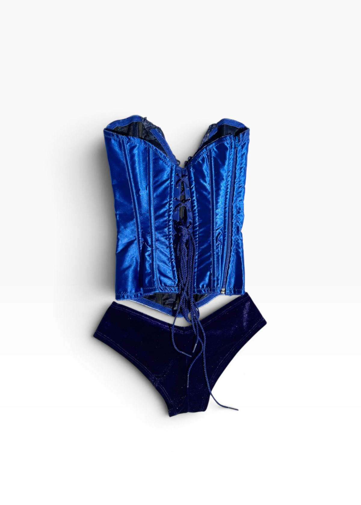 A two-piece lingerie set featuring a shiny royal blue satin corset top with front lacing and matching dark blue velvet briefs, laid flat on a white background.