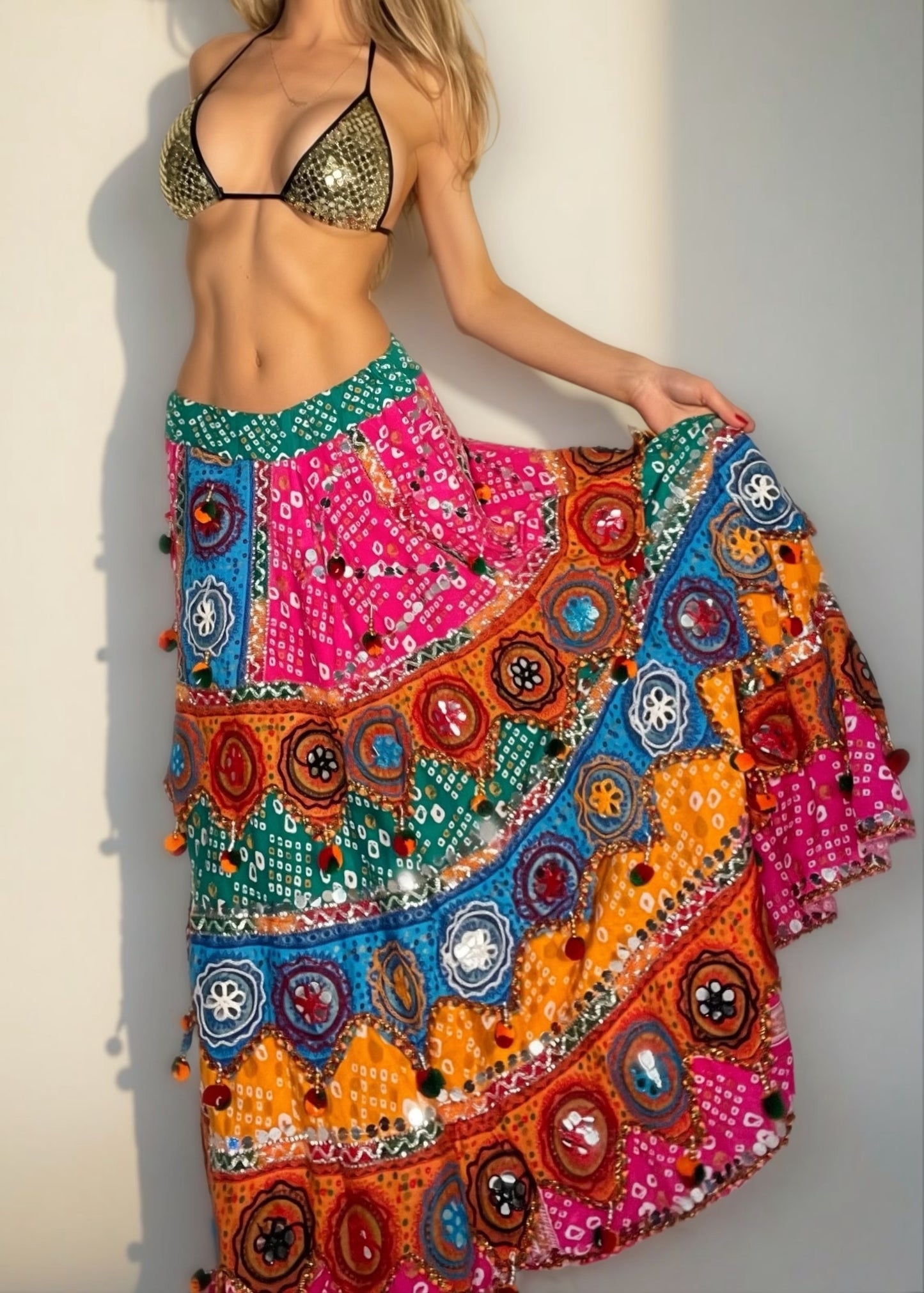 Woman wearing a colorful embroidered skirt with a plain background