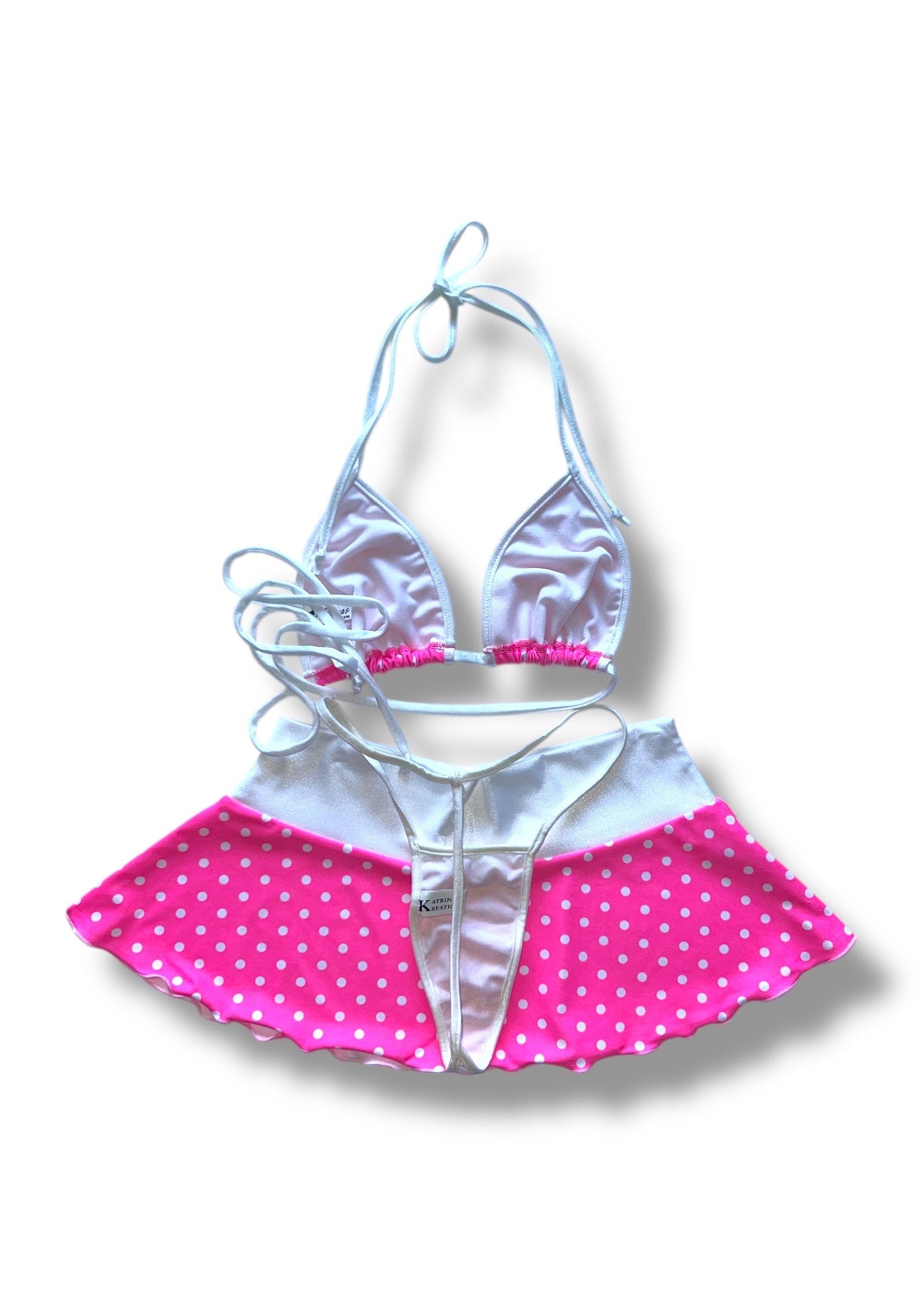Two-piece swimsuit with pink polka dot skirt and white top on a white background