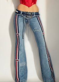 Person wearing a red top and blue jeans with a striped waistband on a plain background