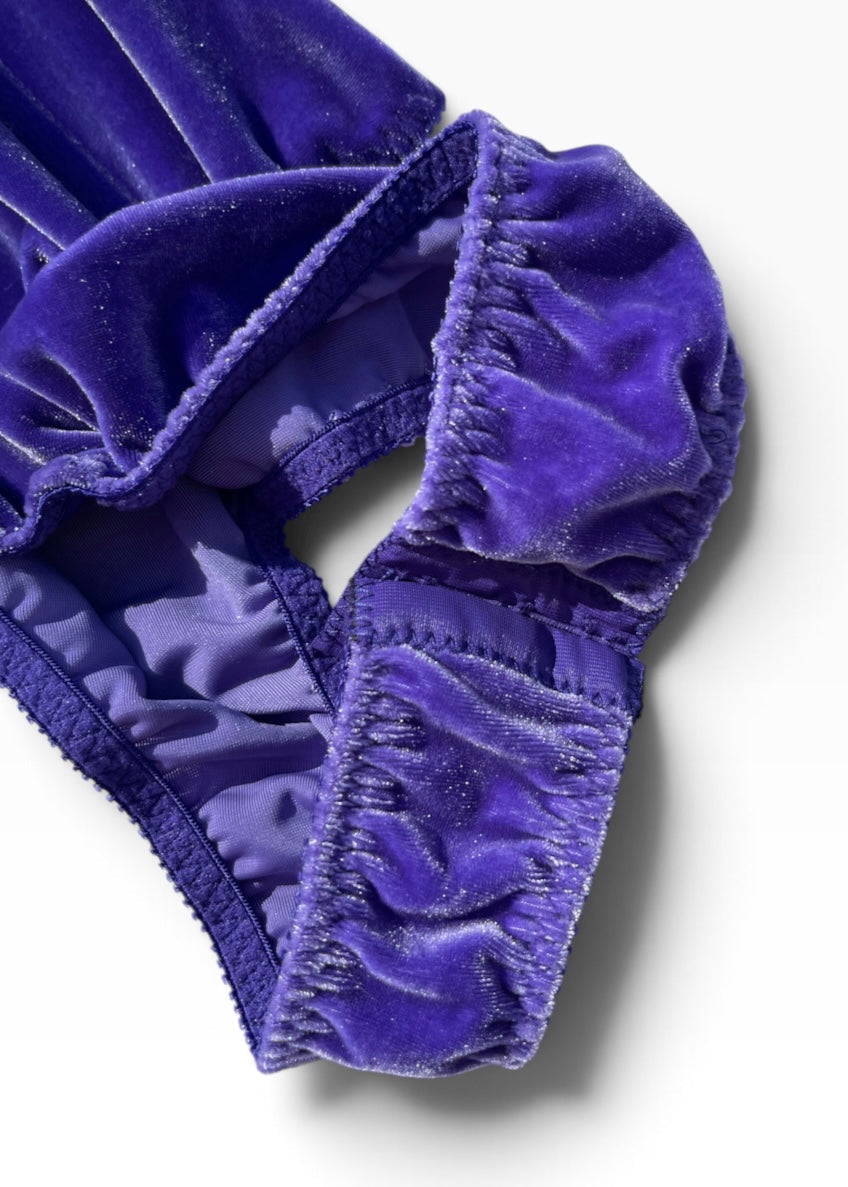 A close-up of a purple velvet lingerie bottom, showing the ruched elastic waistband and satin-like interior lining on a clean white background.