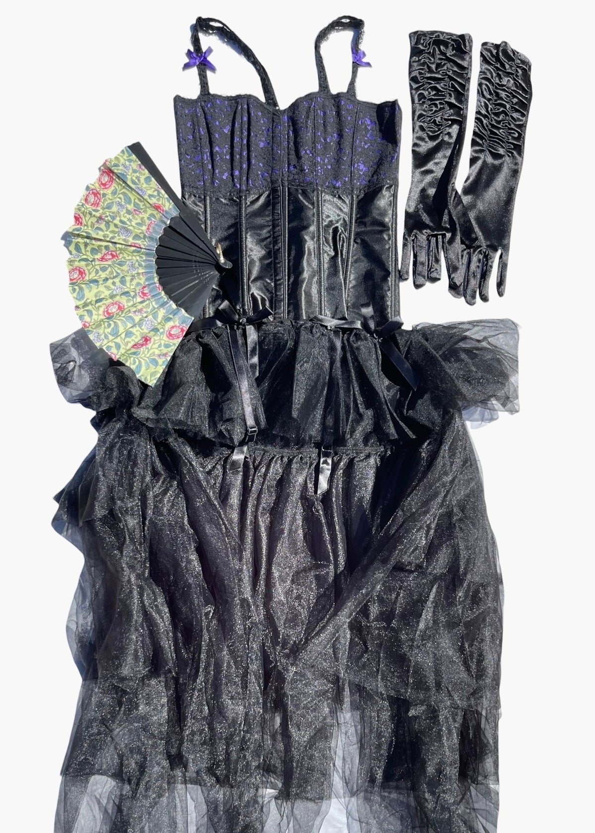 A gothic-style black dress with a corset bodice, sheer ruffled tulle skirt, matching black opera gloves, and a floral-patterned fan, displayed against a plain white background.