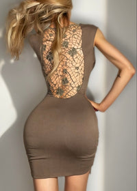 Woman wearing a brown dress with a unique lace back design against a neutral background