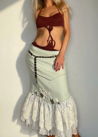 Woman wearing a brown top and light green skirt against a plain background